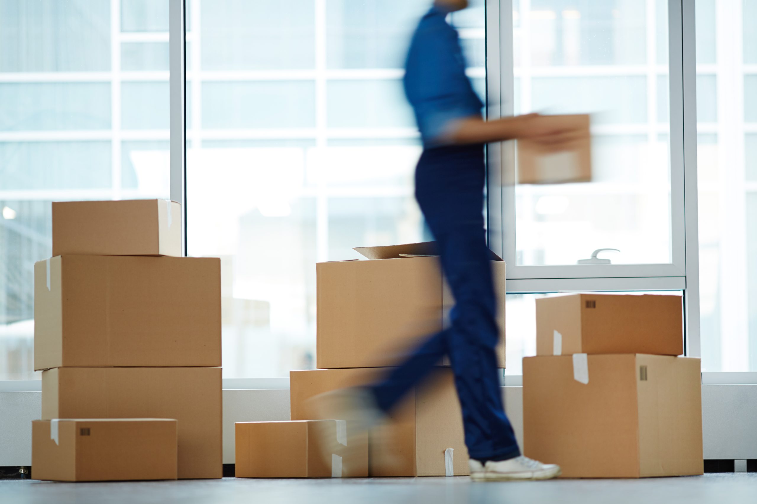 Blurry outline of delivery service staff moving and carrying one of boxes to client office