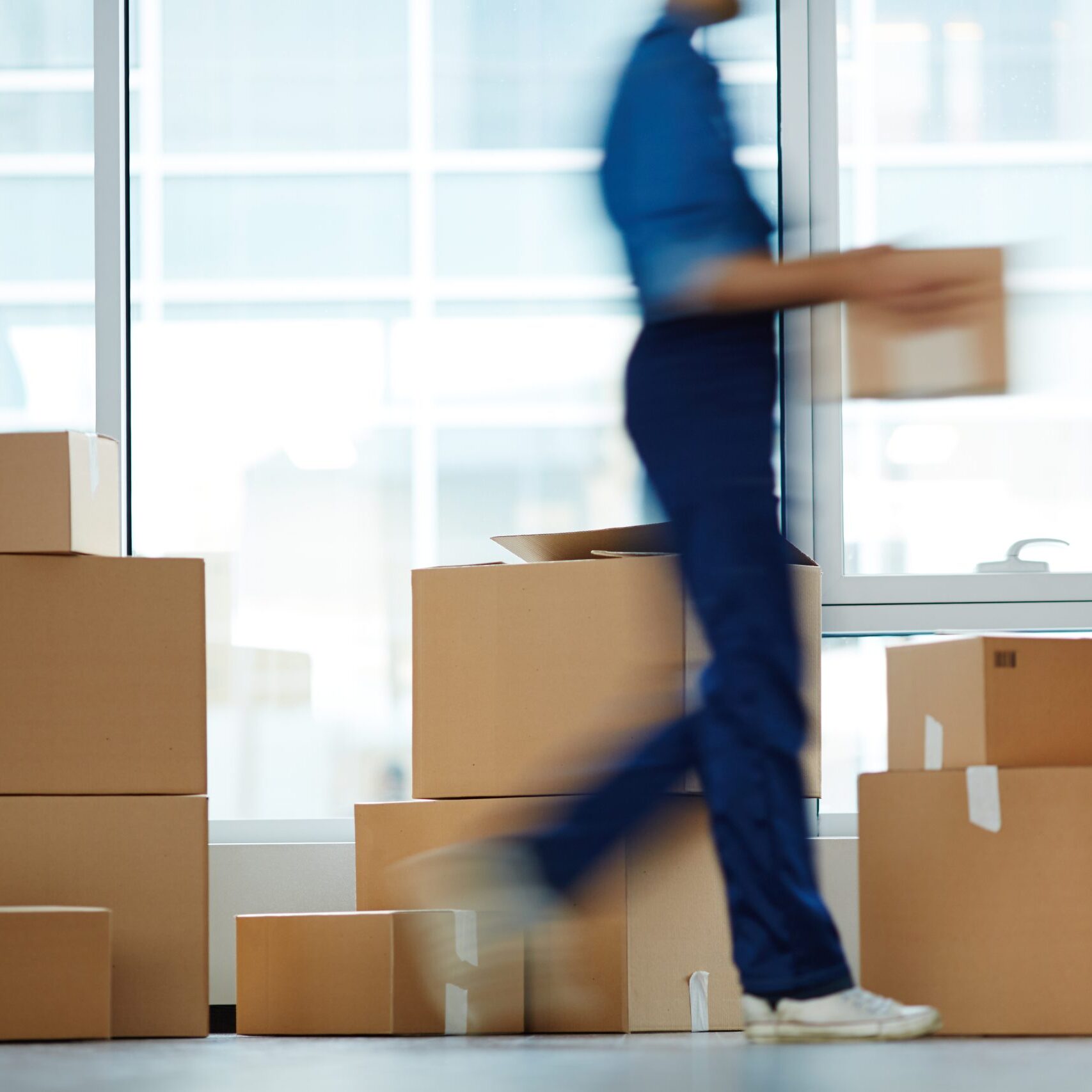 Blurry outline of delivery service staff moving and carrying one of boxes to client office